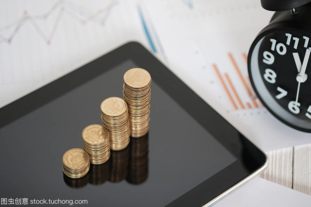 用平板電腦和財務圖進行硬幣棧和鬧鐘的步驟